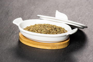 Lot of whole roman caraway seeds in a ceramic stewpan on grey stone