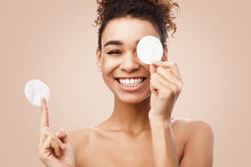 African-american woman removing makeup with cotton pads © Prostock-studio