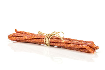 Lot of whole spicy salami stick tyrolini tied by jute isolated on white background