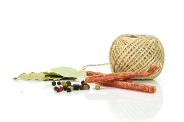Group of two pieces of spicy salami stick tyrolini with black pepper , bay leaf and jute spool isolated on white background