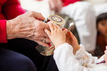 A one year old girl helps her grandmother open a Christmas gift.