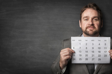 Businessman showing paper calendard in front of him