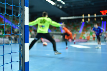 Detail of handball goal post with net and handball match in the background.