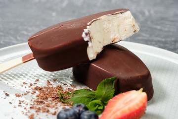 chocolate butter ice cream popsicles on the white plate with fresh summer berries, strawberries, blueberries