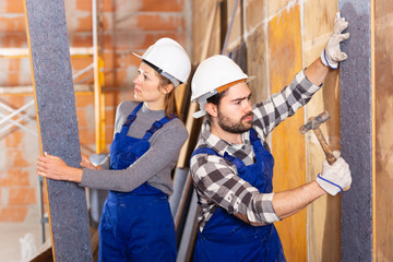 Two professional builders insulate walls inside the house