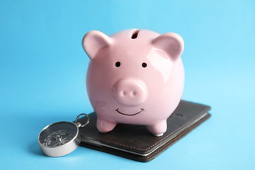 Piggy bank with passport and compass on color background. Travel agency