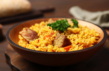 Plate with rice pilaf and meat on wooden table