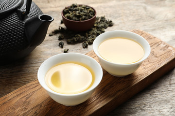 Cups and teapot of Tie Guan Yin oolong on wooden table