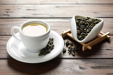 Cup of Tie Guan Yin oolong and chahe with tea leaves on wooden table
