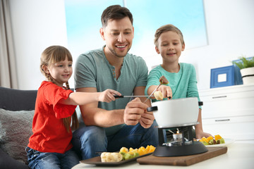 Children enjoying fondue dinner with father at home