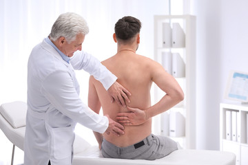 Chiropractor examining patient with back pain in clinic