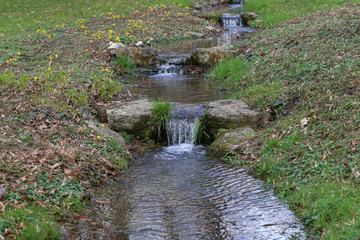 Spring brook with small cascades in the city park