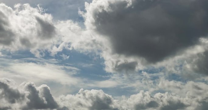 Time lapse clip of gray fluffy curly rolling clouds before storm in windy weather with sun rays