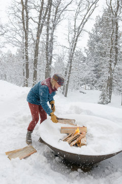 Woman burning firewood during snowstorm, Durango, Colorado, USA