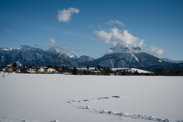 Winterliche Landschaft mit Weg und schneebedeckten Bergen im Hintergrund bei strahlend blauem Himmel