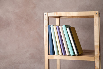 Different books on shelf against color background. Space for text