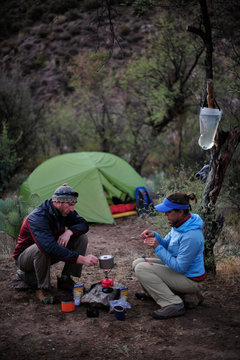Woman and man backpackers prepare dinner with a camp stove at camp close to Charleboise Springs in La Barge Canyon on the Dutchmans Trail in the Superstition Wilderness Area, Tonto National Forest near Phoenix, Arizona November 2011.