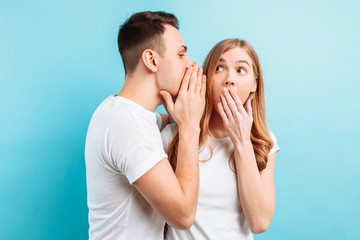 A man whispers in his ear to a woman, telling her something secret, shocking