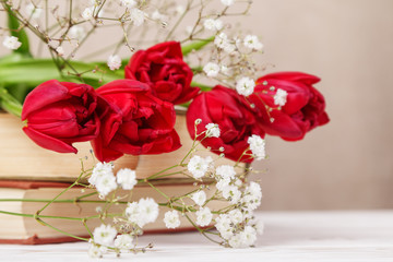 Vintage still Life with a spring red tulips and a books on a beige background. Mother's day, women's day concept