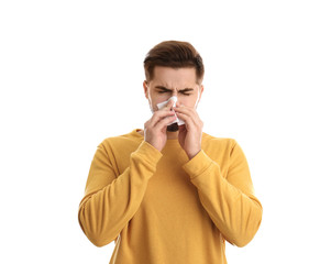 Handsome young man blowing nose against white background