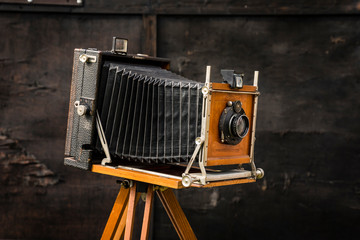 An old large format camera on a wooden tripod.