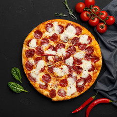 Pepperoni pizza and cooking ingredients on black background