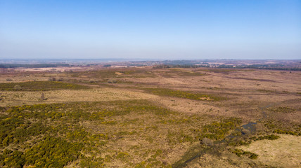 Aerial view of the New Forest National Park with heathland and waterway under a majestic blue sky.