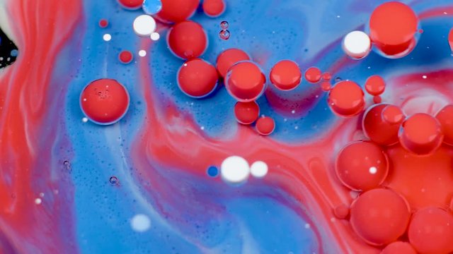 Amazing red and blue bubbles of paint on the oil surface. Paint in oil.