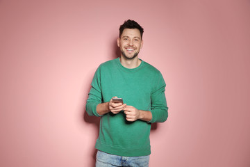 Handsome man with mobile phone on color background