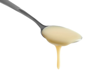 Spoon with condensed milk on white background, closeup. Dairy product