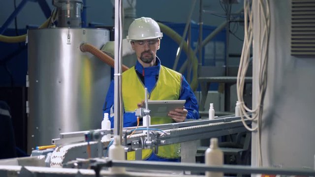 Male technician is observing plastic bottles moving along the belt