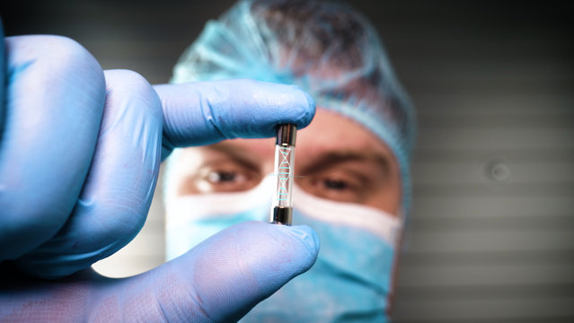 Scientist in his future laboratory holds a test tube containing DNA and is able to control the evolution of man thanks to holography. Concept of: DNA, technology, augmented reality.