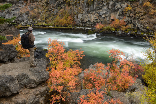 Man with backpack along Deschutes River at Dillon Falls in fall
