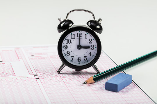 School Students hands taking exams, writing examination holding pencil on optical form of standardized test with answers sheet doing final exam in classroom. Education assessment Concept. Soft focus