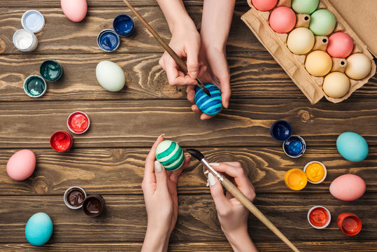 top view of women painting easter eggs at wooden table