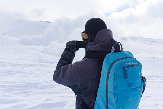 A snowboarder taking a picture on his phone of the fume holes on Mt. Asahi