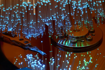 Close up on opened computer hard disk drive with colored optic fiber.
