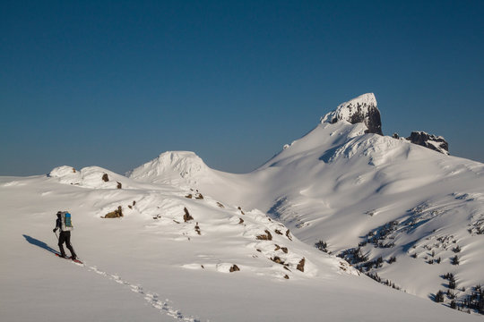 Man snowshoeing up hill in Garibaldi Provincial Park with view of Black Tusk mountain