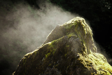 Sun causes evaporation and steam to come off a large boulder.