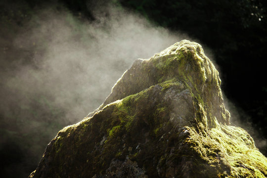 Sun causes evaporation and steam to come off a large boulder.
