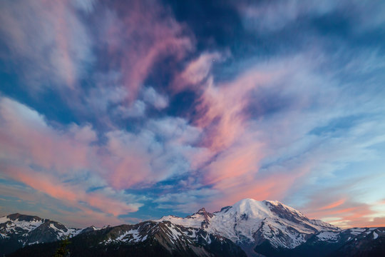 Alpenglow illuminates the clouds above Mount Ranier in Mount Ranier National Park.