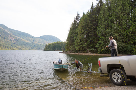 Two men launching boat before fishing in Hicks Lake, Harrison Hot Springs, British Columbia, Canada