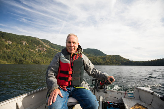 Fisherman sitting in motorboat, Hicks Lake, Canada