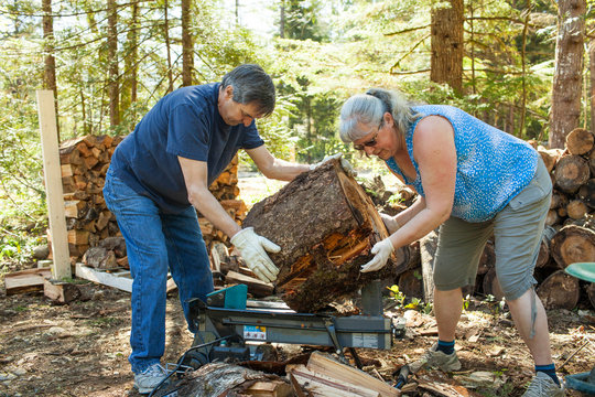 Couple splitting firewood using wood splitter machine