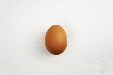 Isolated natural brown chicken egg on white wooden table with soft shadow below the egg