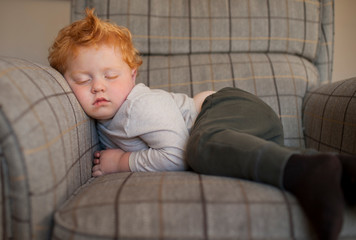 Toddler boy asleep in plaid armchair