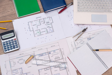 Top view of house plan with laptop, calculator and pencils