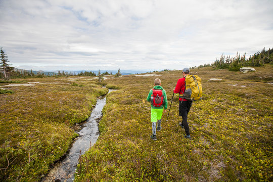 Father and son hiking beside alpine stream, Merritt, British Columbia, Canada