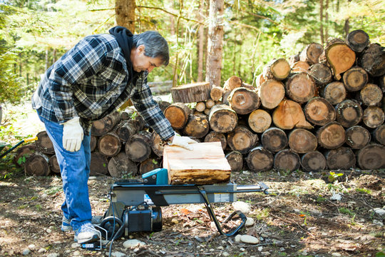 Senior man using wood splitter for firewood