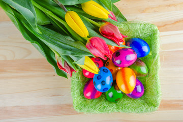 colorful easter eggs and tulip flowers on wooden table